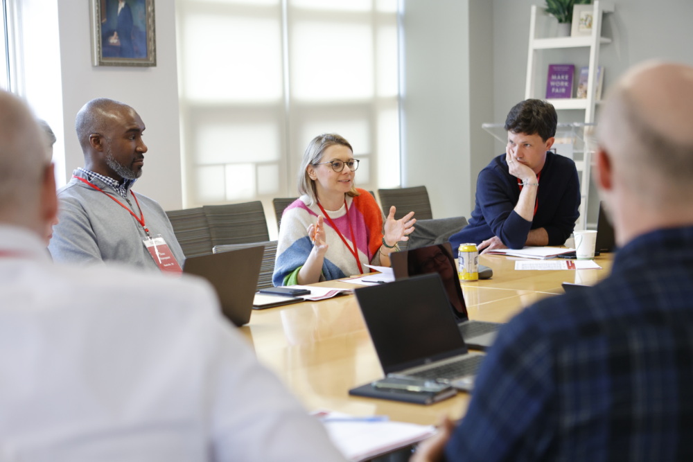 BHCLI-Collaboration-Day 2- group of men at a top with a women speaking
